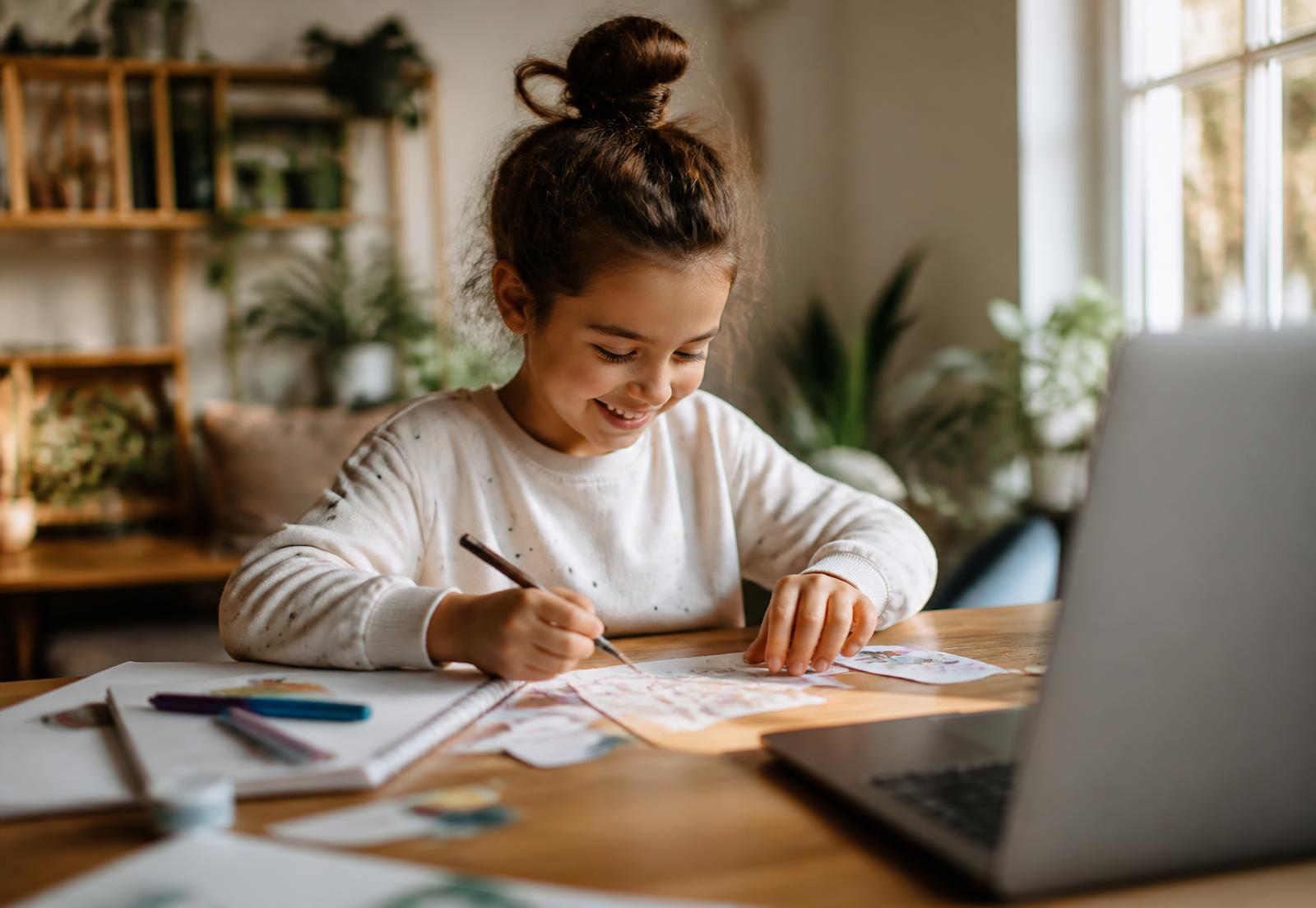 A young child drawing and learning at a table during a live online Turkish lesson